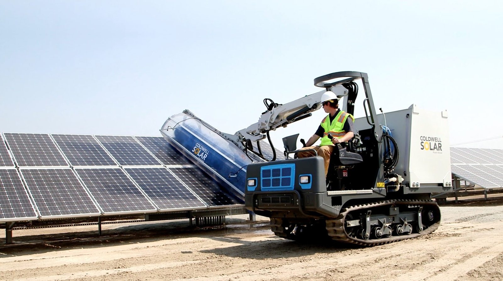 Coldwell Energy machine cleaning a row of ground-mounted solar panels on California agricultural land.